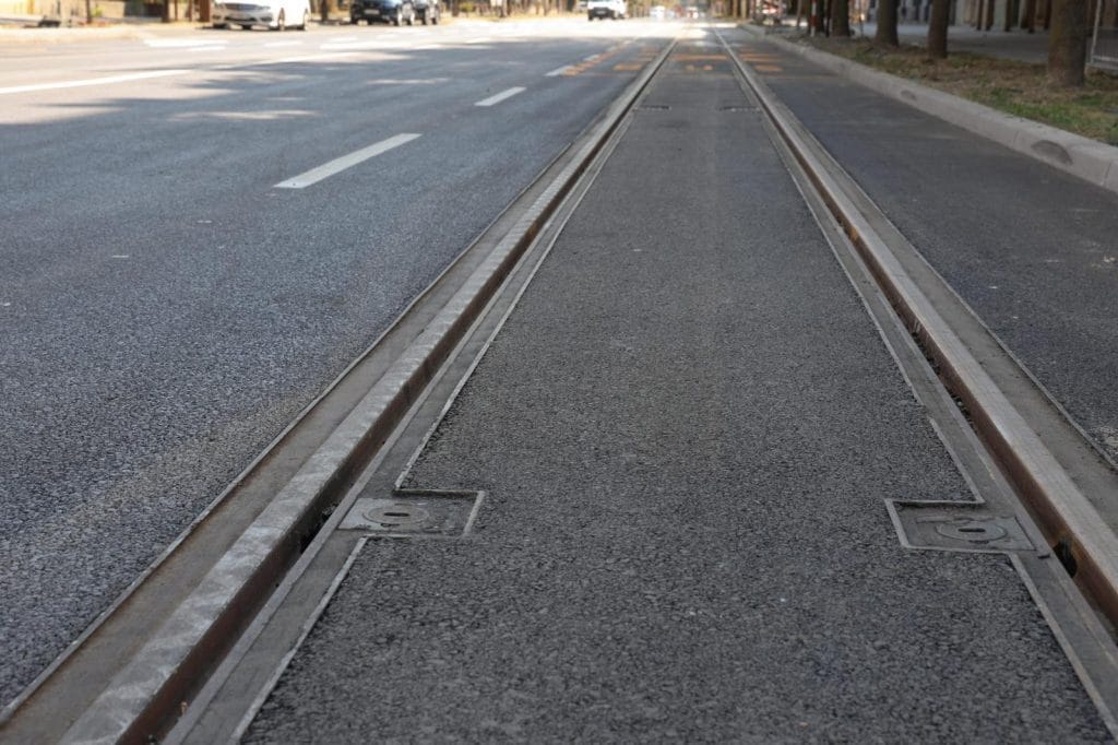 Prikazuje novi dio tramvajske pruge u Osijeku, s fokusom na tračnice i beton, te logom tvrtke Swietelsky.